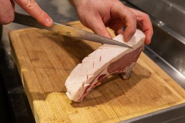 Knife scoring the fat on a Berkshire pork chop